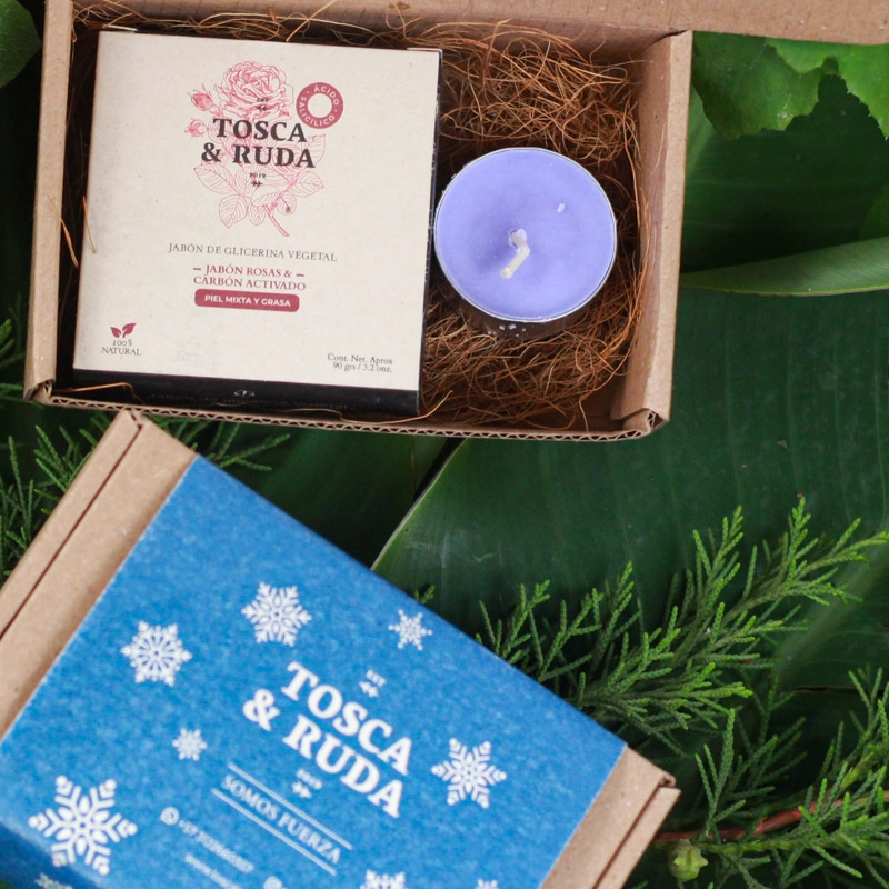 jabon en su caja, vela morada de lavanda sobre plantas y caja cerrada azul al lDO