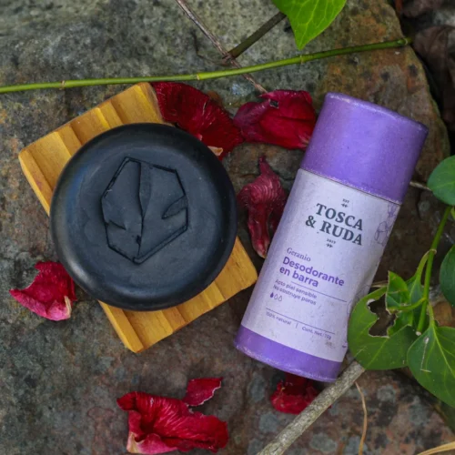 jabon negro osbre jabonera de madera con desodorante morado, sobre piedra con flores