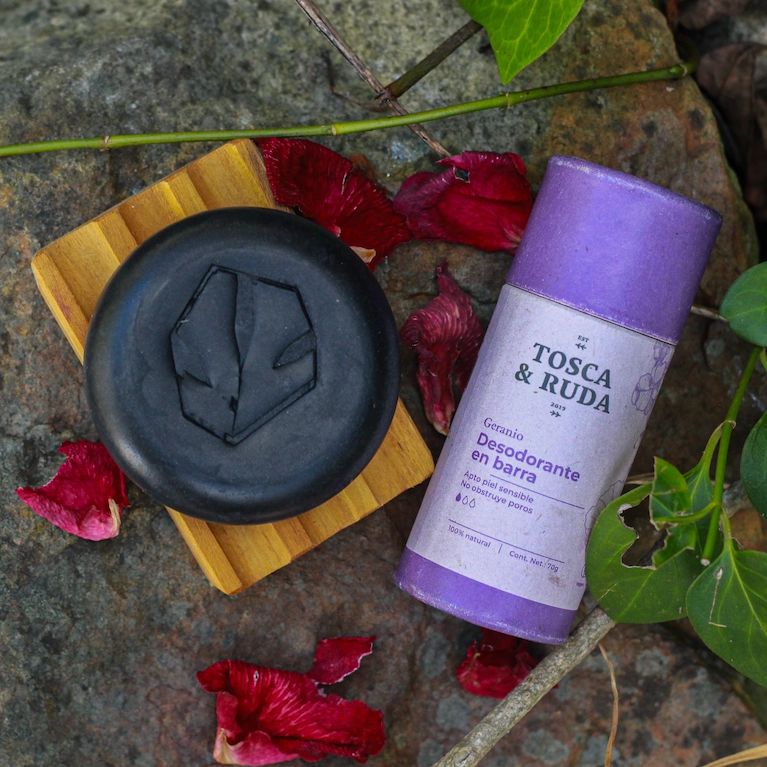 jabon negro osbre jabonera de madera con desodorante morado, sobre piedra con flores